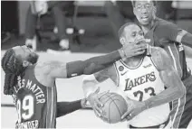  ?? MARK J. TERRILL/AP ?? The Lakers’ LeBron James is hit in the face as he drives against the Heat’s Jae Crowder (99) and Bam Adebayo during the first half in Game 6 of the NBA Finals on Oct. 11 in Lake Buena Vista. The Heat gather at camp Sunday for this first time since this game.