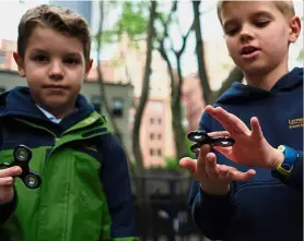  ?? — AFP ?? Kids will be kids: Tom (left) and his brother Louis playing with fidget spinners in a park in New York.