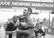  ?? LUCAS FINTON / THE COMMERCIAL APPEAL ?? Tyler Fennema, from Horn Lake, hugs an unidentified man after completing the 2021 St. Jude Memphis Half Marathon on Saturday, in Downtown Memphis.