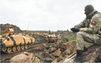  ?? Bulent Kilic / AFP / Getty Images ?? Turkish troops gather near the Syrian border in the town of Hassa. On Saturday, Turkey opened a new offensive against the Kurdish militia in the Syrian city of Afrin.