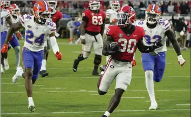  ?? (AP/John Raoux) ?? Georgia running back Daijun Edwards (center) runs for a 22-yard touchdown against Florida during the second half Saturday in Jacksonvil­le, Fla. The top-ranked Bulldogs defeated the Gators 42-20.
