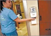  ?? ANTONIO PEREZ/CHICAGO TRIBUNE ?? Registered nurse Claire Nelson uses a hand sanitizer before seeing a patient at Elmhurst Hospital on Nov. 25. Infections are a major problem in hospitals, and some, such as Elmhurst Hospital are tackling this by installing technology to track when and where employees wash their hands.