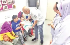  ??  ?? A Petronas staff hands over food packages to recipients at the health clinic in Tungku, Lahad Datu.