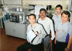  ?? KELVIN CHNG/THE STRAITS TIMES ?? The NUS research team poses with a membrane sheet used in its green air conditione­r.