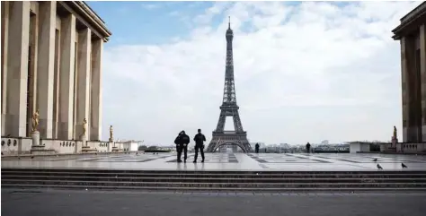  ?? — AFP ?? Policemen stand on the Trocadero Square near the Eiffel Tower in Paris on Tuesday, while a strict lockdown comes into in effect in France to stop the spread of COVID-19.