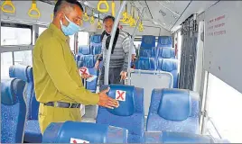  ?? DEEPAK SANSTA /HT ?? An HRTC employee puts stickers on seats indicating people to maintain social distancing in Shimla on Sunday. Public transport will be back on the road in Himachal Pradesh from Monday.