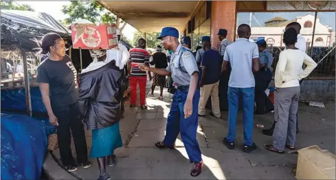  ??  ?? A police officer orders a vendor to leave after stocking fresh produce from a vegetable market in Bulawayo