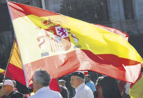  ??  ?? People wave a Spanish flag during a demonstrat­ion calling for unity, Madrid, Oct. 28.