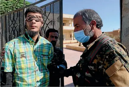  ??  ?? Members of Syrian Democratic Forces escort a blindfolde­d civilian detainee suspected to be a member of Islamic State militants in Raqqa.