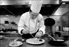  ??  ?? Wu Xinhua works on the final touch of a dish at Dan Cha Fan restaurant in Wuzhen. The helmsman of the popular eatery creates dishes with inspiratio­n from different styles of cuisine.