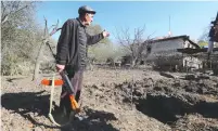  ?? ( Reuters) ?? LOCAL RESIDENT Alexei Agadzhanov holds a rifle while showing a crater following shelling on Saturday in the settlement of Shosh in Nagorno- Karabakh.