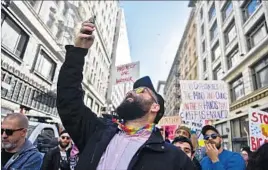  ?? Stuart Palley For The Times ?? ERIC HOFF takes a photo of demonstrat­ors gathering in Pershing Square for the L.A. women’s march. Organizers put the number of participan­ts at 750,000.