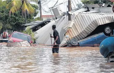  ?? DELMER MARTINEZ/AP ?? A man wades through a flooded street Nov. 6 in Planeta, Honduras, after Hurricane Eta raked parts of Central America.