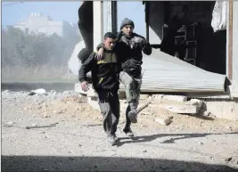  ??  ?? The Associated Press This photo released by the Syrian Civil Defense White Helmets shows a Syrian Civil Defense member helping a man wounded after airstrikes and shelling hit Ghouta, a suburb of Damascus, Syria, on Wednesday.