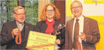  ?? FOTO: EZEREX ?? Zum Abschied gibt es Wurst: Dekanatsre­ferentin Kerstin Leitschuh mit den Dekanen Sigmund Schänzle und Hellger Koepff.