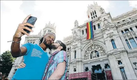  ?? JUAN CARLOS HIDALGO / EFE ?? Dos hombres se hacen un selfie con un beso ante el Ayuntamien­to de Madrid con la bandera arco iris
