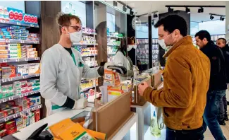  ??  ?? Le 2 avril 2020, un panneau de protection est installé devant le comptoir d’une pharmacie à Paris.