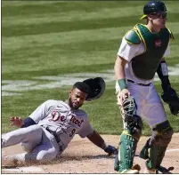  ??  ?? Detroit Tigers’ Willi Castro, left, slides home to score behind Oakland Athletics catcher Sean Murphy during Sunday’s loss.