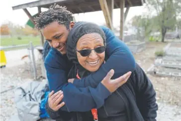  ?? The Associated Press ?? Tyrone Anthoney hugs Aster Bekele last month in Indianapol­is. Bekele wanted to teach at-risk kids how to garden. Then the city’s homicide rate soared, with most of the killings occurring around the community center where Bekele and the teens tended...