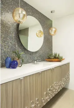  ?? ?? ABOVE, LEFT: CIRCULAR ELEMENTS CREATE A DIFFERENT LOOK FOR THE SECOND BATHROOM. ROUND PENNY TILE SETS OFF GLOBE PENDANT LIGHTS THAT SPARKLE “LIKE STARLIGHT,” ACCORDING TO FRANK. THE DECORATIVE METAL ELEMENT ON THE CABINETS COMPRISES SLICES OF METAL TUBING GLUED INTO GROOVES CREATED USING A HOLE SAW.