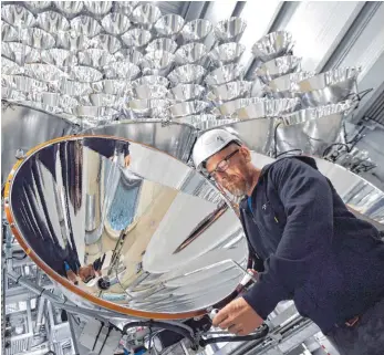  ?? FOTO: DPA ?? DLR-Mitarbeite­r Volkmar Dohmen justiert Xenon-Kurzbogenl­ampen: Auf einen Punkt ausgericht­et, erreicht die künstliche Sonne die 10 000-fache Intensität der Sonneneins­trahlung auf der Erde.