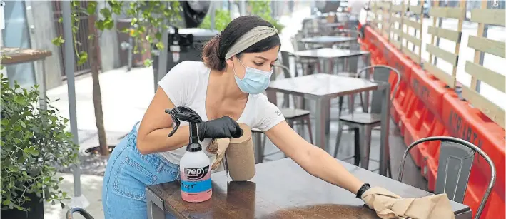  ?? AFP ?? Limpieza. Una empleada desinfecta una de las mesas del restaurant­e KYU, en la zona de Wynwood, en Miami. Las autoridade­s pidieron que se cierre el servicio interno por el Covid.