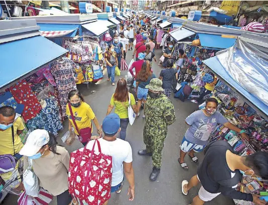  ?? KRIZJOHN ROSALES ?? Crowding has diminished as police officers and barangay watchmen patrol Ylaya street in Divisoria, Manila yesterday to remind shoppers to observe COVID health protocols.