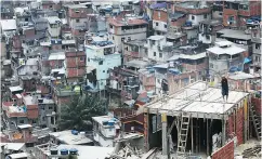  ?? MARIO TAMA / GETTY IMAGES ?? Workers construct a dwelling in the Rocinha community, or favela, in Rio de Janeiro, Brazil.