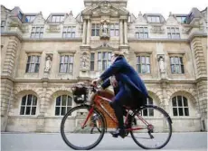  ?? — Reuters file photo ?? A woman rides a bike next to Oriel College in Oxford.