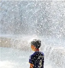  ?? — Reuters photo ?? A boy plays in a fountain to cool down at a park during a hot summer day in Tokyo, Japan.