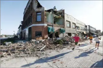  ?? CHARLIE NEIBERGALL — THE ASSOCIATED PRESS ?? A local resident runs past a tornado-damaged building on Main Street, Thursday in Marshallto­wn, Iowa. Several buildings were damaged by a tornado in the main business district in town including the historic courthouse.