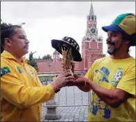  ?? AP/DMITRI LOVETSKY ?? Brazilian fans hold a replica of the World Cup trophy Monday near the Kremlin in Moscow. The 21st World Cup begins Thursday when host Russia takes on Saudi Arabia.