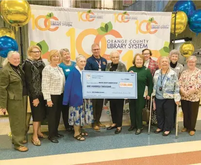  ?? CRISTÓBAL REYES/ORLANDO SENTINEL ?? Orange County Library System CEO Steve Powell, center, is joined by members of the Sorosis of Orlando Women’s Club, which donated $100,000 to the library on Saturday. The money will be used to reintroduc­e the Bookmobile program, a roving mobile library that ran from 1949 to 1979.