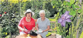  ?? FOTO: UWE MISERIUS ?? Im bunt-blühenden Garten, zwischen duftenden Rosen und kräftig strahlende­n Blüten, ließ es sich Besucherin Heidi Dunkel (rechts) bei einer Tasse Kaffee im Rosen-Pavillon von Gartenbesi­tzerin Ilona Mierbach richtig gut gehen.