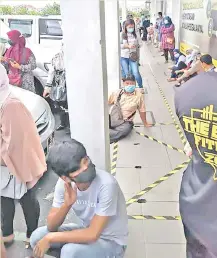  ??  ?? Customers, some seen sitting on the walkway, waiting outside Maybank Prima Square.