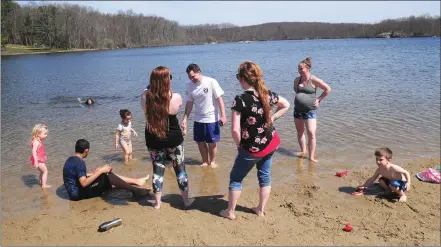  ?? Ernest A. Brown photo ?? Friends gather along the shore at the beach area of Stephen Olney Pond at Lincoln Woods State Park in Lincoln Wednesday, where temperatur­es soared into the mid-80s for the first time since last October.