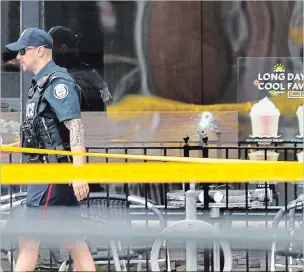  ?? RICHARD LAUTENS TORONTO STAR ?? An officer walks past the bullet hole in the window of a Second Cup Coffee shop after a mass shooting on the Danforth.