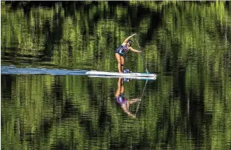  ?? JOHN SPINK / JSPINK@AJC.COM ?? Grant Park resident Dana Bittenbend­er zips across Stone Mountain Lake on her paddleboar­d Thursday, taking advantage of the hot summer weather to train for the Chattajack on Oct. 27. The Chattajack is a paddleboar­d/kayak endurance race being held in Chattanoog­a, Tennessee.