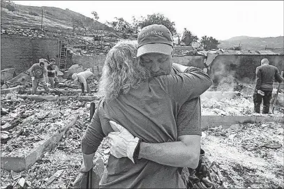  ?? [RINGO H.W. CHIU/THE ASSOCIATED PRESS] ?? Craig Bolleson hugs his friend in his burned out home Monday in the Sunland-Tujunga section of Los Angeles. Wildfires forced thousands to flee their homes across the West during a sweltering, smoke-shrouded holiday weekend.