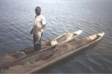  ??  ?? A Mobaye refugee with a fish, is pictured on Marc1 in Longo, in Damara district.