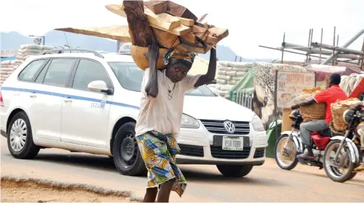  ?? PHOTO
ABUBAKAR YAKUBU ?? A woman carrying pieces of wood near Dei-Dei Building Material Market in Abuja on Wednesday.