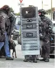  ??  ?? Counter-terrorism officers at the address in Sunbury on Thames with a blast shield