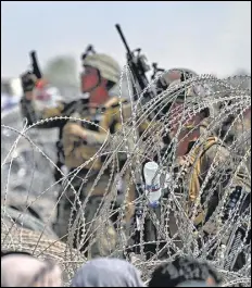  ?? AFP ?? Crowds gather on a roadside (left) near the military section of the airport in Kabul on Friday, hoping to leave the country; a US soldier shoots in the air while standing guard behind barbed wire.