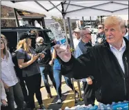  ?? AP/EVAN VUCCI ?? President Donald Trump and first lady Melania Trump hand out water Monday in Lynn Haven, Fla., during a visit to areas devastated by Hurricane Michael.