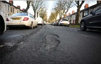  ?? — AFP photos by Paul Ellis ?? A car is driven past a pothole in a damaged road in Liverpool, north west England.