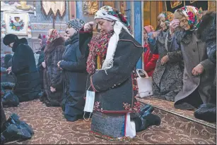  ??  ?? Mahnych, wearing a Hutsul’s traditiona­l colorful clothes, crosses herself holding a face mask in her hand because she said other worshipper­s forced her to take off her mask “in order not to remind about the contagion” in the Holy Trinity church in Iltsi, Ukraine.