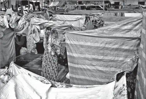  ?? KING RODRIGUEZ ?? LIFE AFTER THE FIRE. 63-year-old Casmina Diraman, one of the fire victims in three barangays that started in Isla Verde four months ago, arranges her belongings outside her temporary quarters in one of the evacuation sites, yesterday. They’re still...