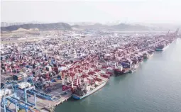  ??  ?? Cargo ships are moored under cranes as shipping containers stand at the Qingdao Qianwan Container Terminal in this aerial photograph taken in Qingdao, China. (Bloomberg)