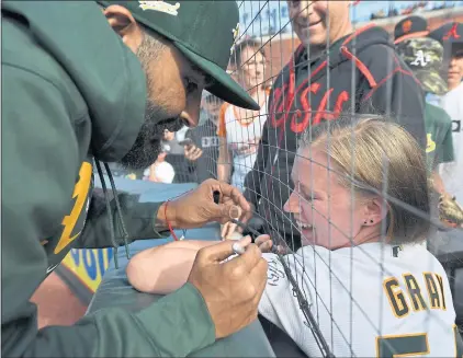  ?? JOSE CARLOS FAJARDO — STAFF PHOTOGRAPH­ER ?? Oakland pitcher Sergio Romo autographs the jersey of A’s fan Alex Dowden, of Novato, before the start of the Athletics’ game against the Giants at Oracle Park in San Francisco on Saturday. The game was the Bay Area’s first MLB game to have fans since COVID-19 restrictio­ns were lifted.