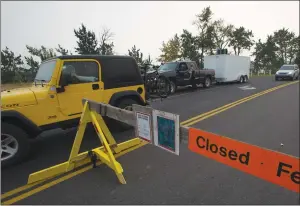  ?? LETHBRIDGE HERALD PHOTO IAN MARTENS ?? Vehicles leave the park entrance as RCMP man the barricade near the intersecti­on of Highways 5 and 6 following an evacuation order due to the Kenow fire that threatens Waterton Lakes National Park and Waterton townsite.